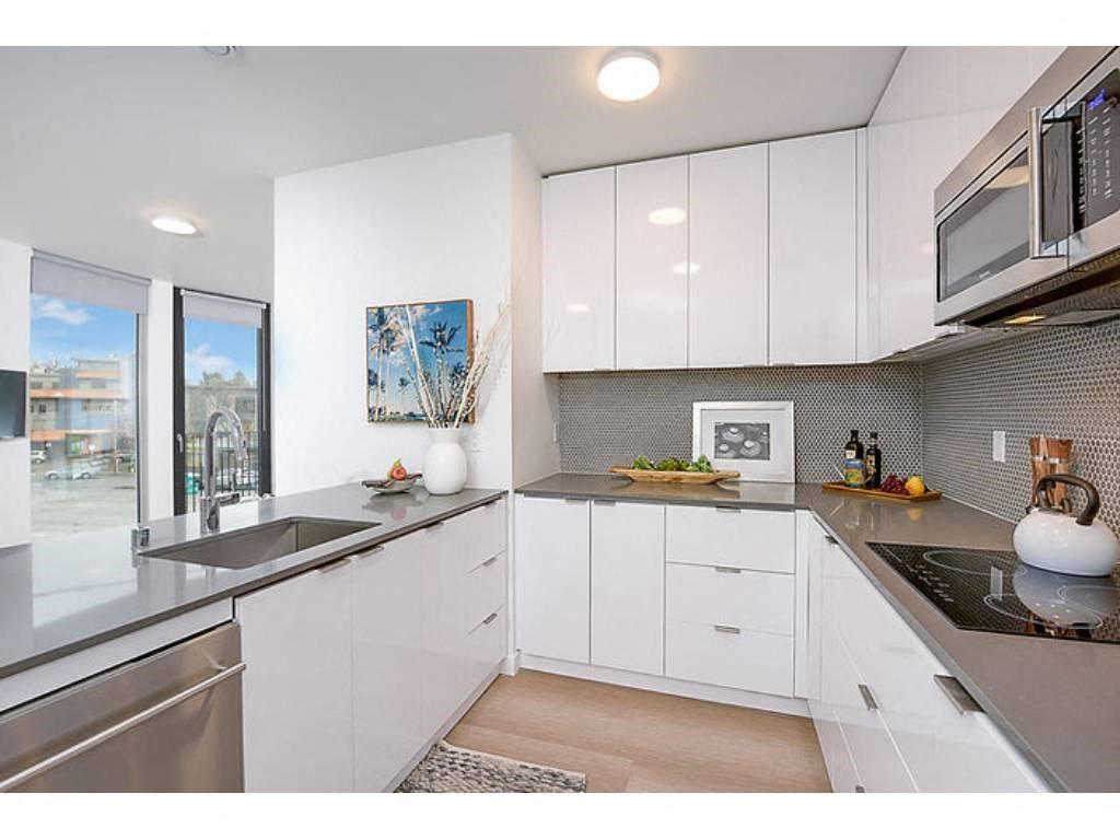 Fremont Apartments for Rent - Inspire Fremont - Kitchen with Stainless Steel Appliances, Granite Countertops, White Cabinets, and Hardwood Style Flooring