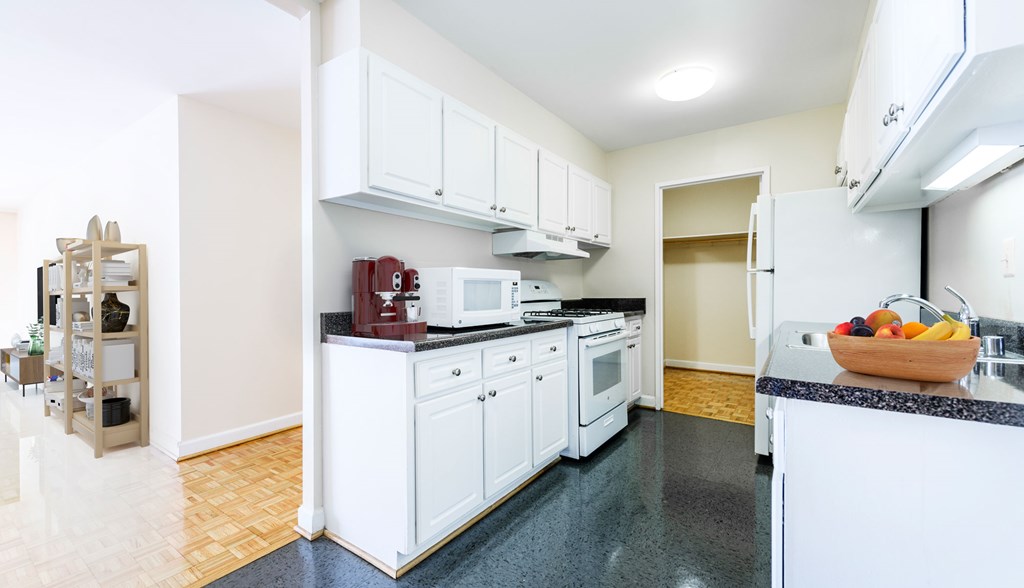 A kitchen with white cabinets and black countertops.