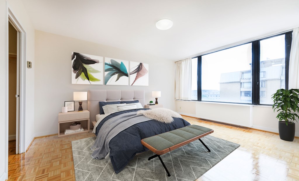A bedroom with a bed, a bench, and a potted plant.