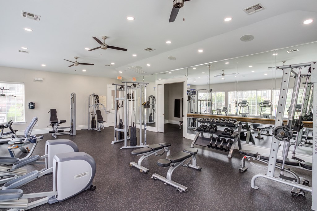 a gym with cardio equipment and weights on the floor and windows