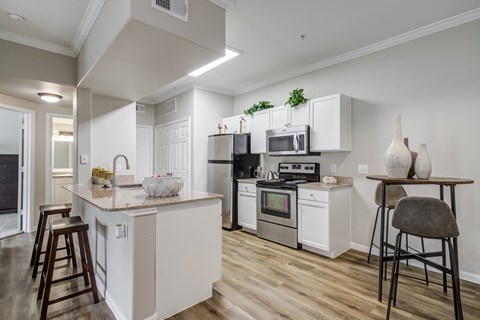a kitchen with white cabinets and appliances and a bar with stools