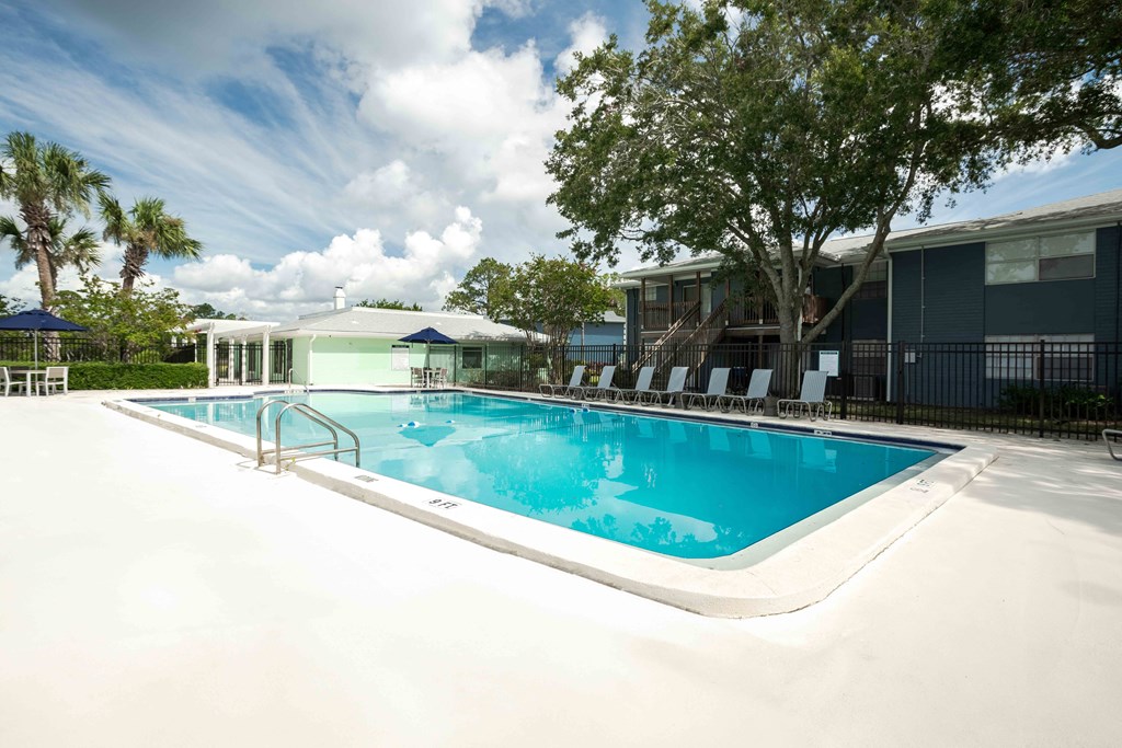 Outdoor pool with clear blue water and nearby relaxation areas at The Marley at Trout River in Jacksonville, Florida.