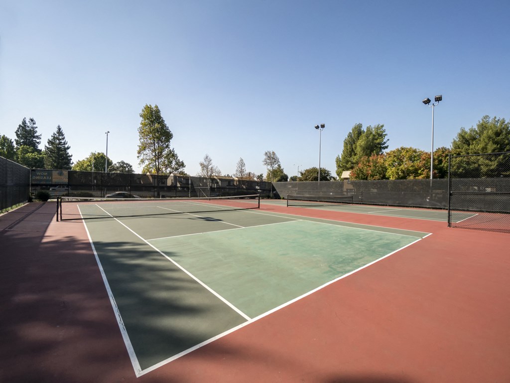 a tennis court with a fence around it on a sunny day