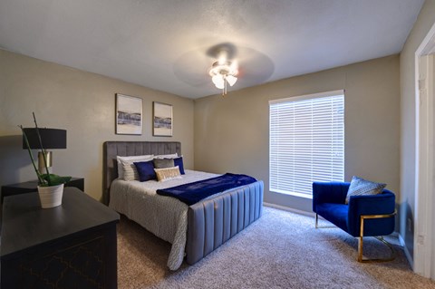 a bedroom with a bed and a chair and a window
