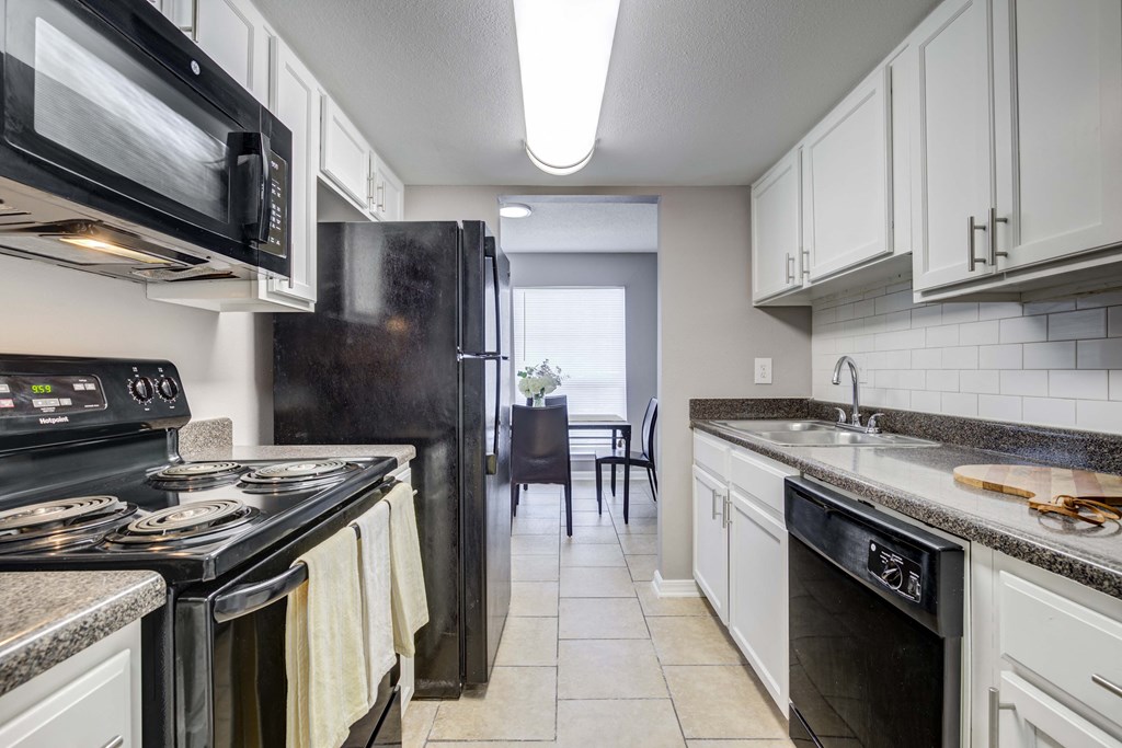 Westchase Apartments in Harvey LA photo of a kitchen with white cabinets and black appliances and a black refrigerator