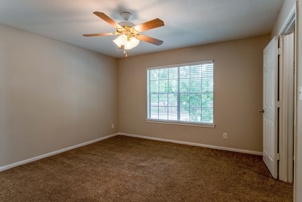 Pet-Friendly Apartments in Houston, TX – Westchase Forest – Photo of bedroom with large window, ceiling fan, and plush carpeting