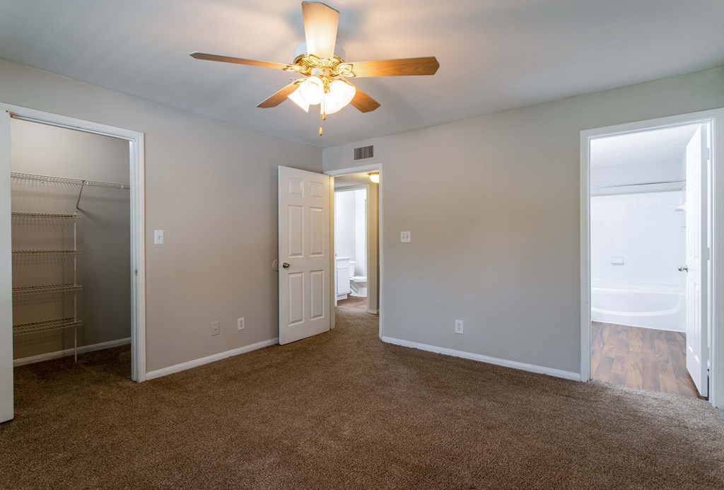 Pet-Friendly Apartments in Houston, TX – Westchase Forest – Photo of master bedroom with large closet, ceiling fan and plush carpeting