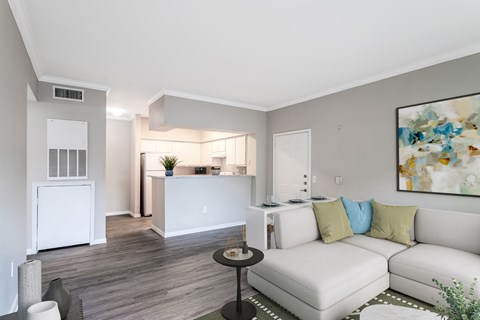 A living room with a white couch and a painting on the wall.