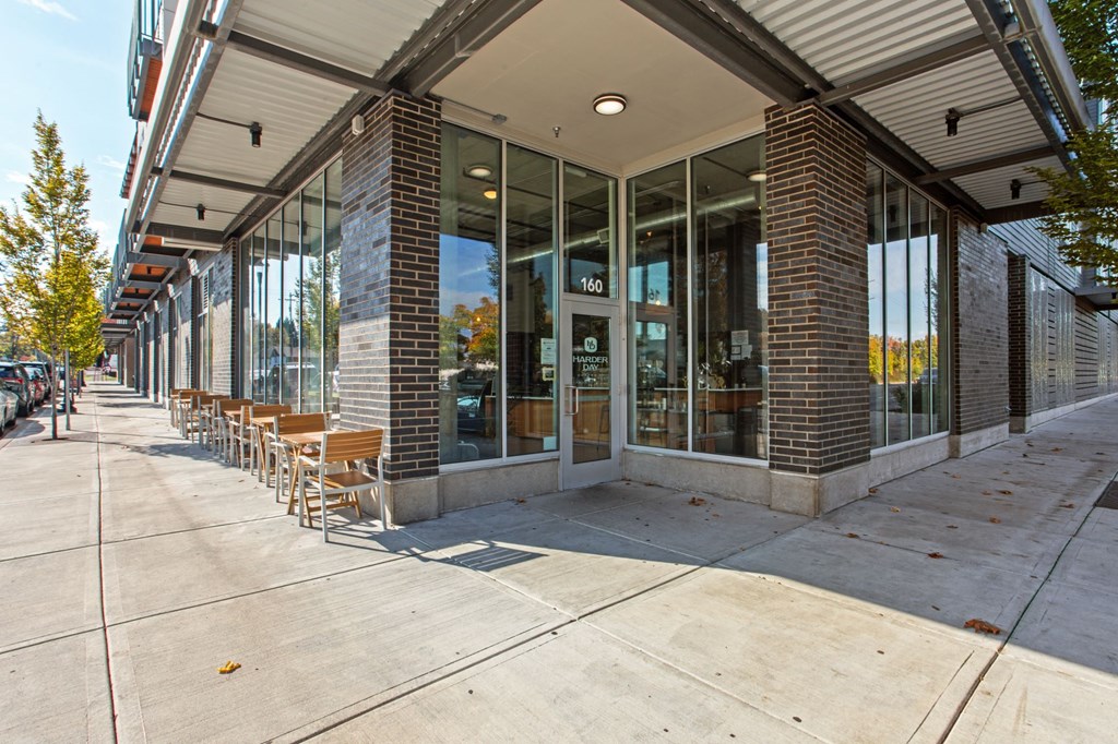 A building with a glass facade and a row of wooden chairs outside.