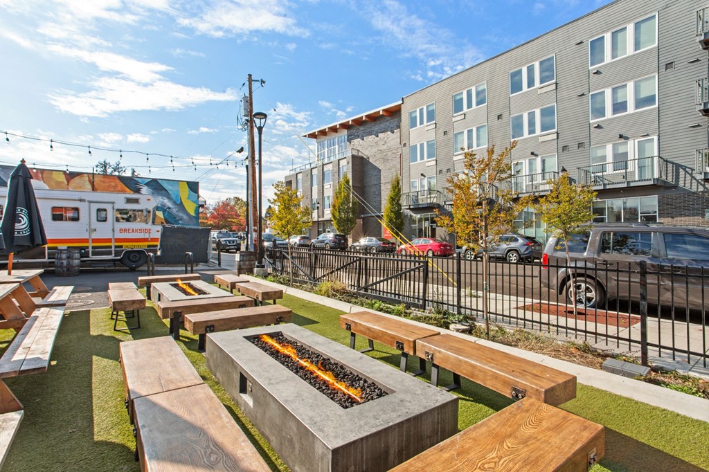 A sunny day at an outdoor seating area with wooden benches and a food truck in the background.