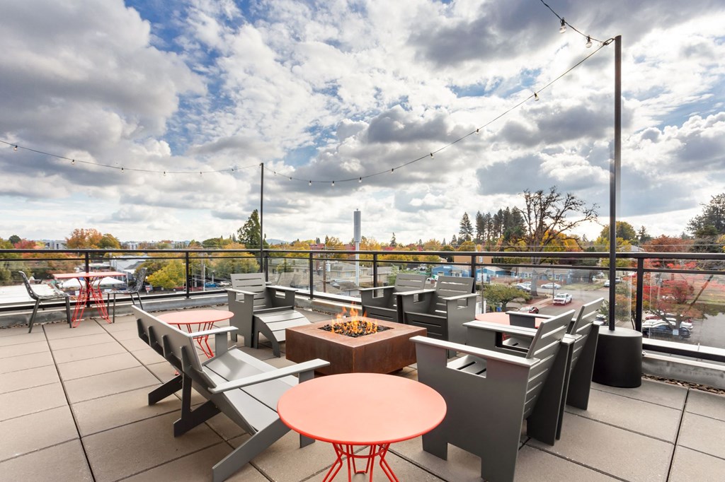 A patio with tables and chairs overlooking a parking lot.