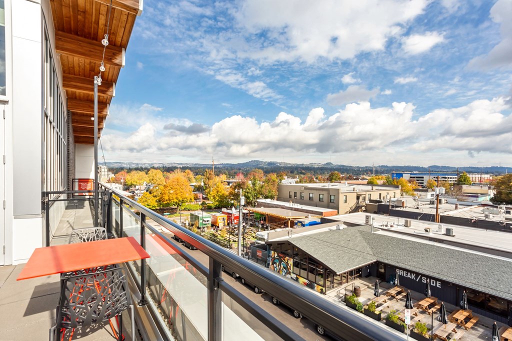 A balcony with a table and chairs overlooks a cityscape.