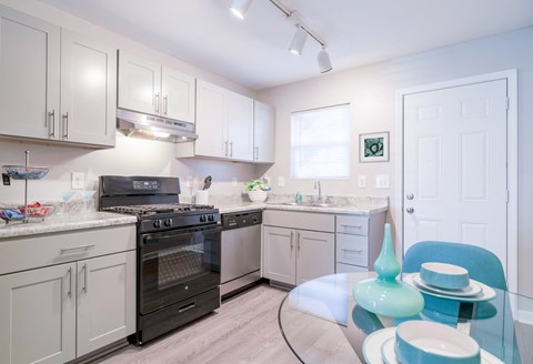 a kitchen with white cabinets and stainless steel appliances and a glass table