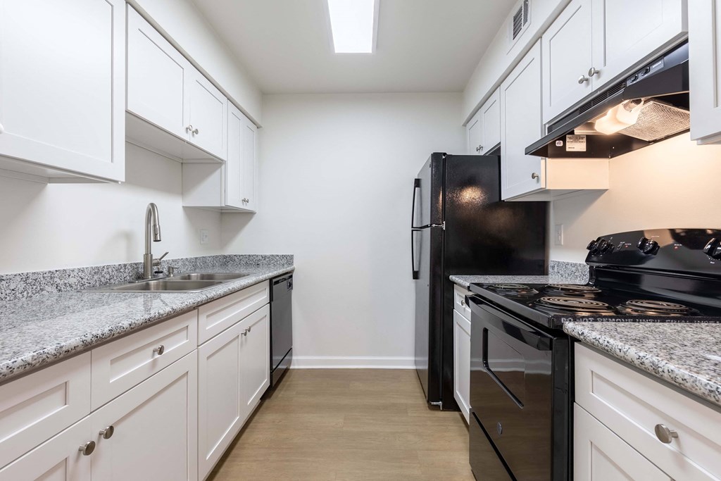 Whitney Manor Apartments in Gretna, LA photo of a kitchen with white cabinets and black appliances