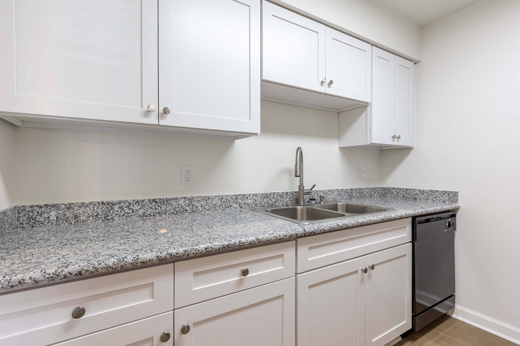 Whitney Manor Apartments in Gretna, LA photo of  a kitchen with white cabinets and granite counter tops and a sink