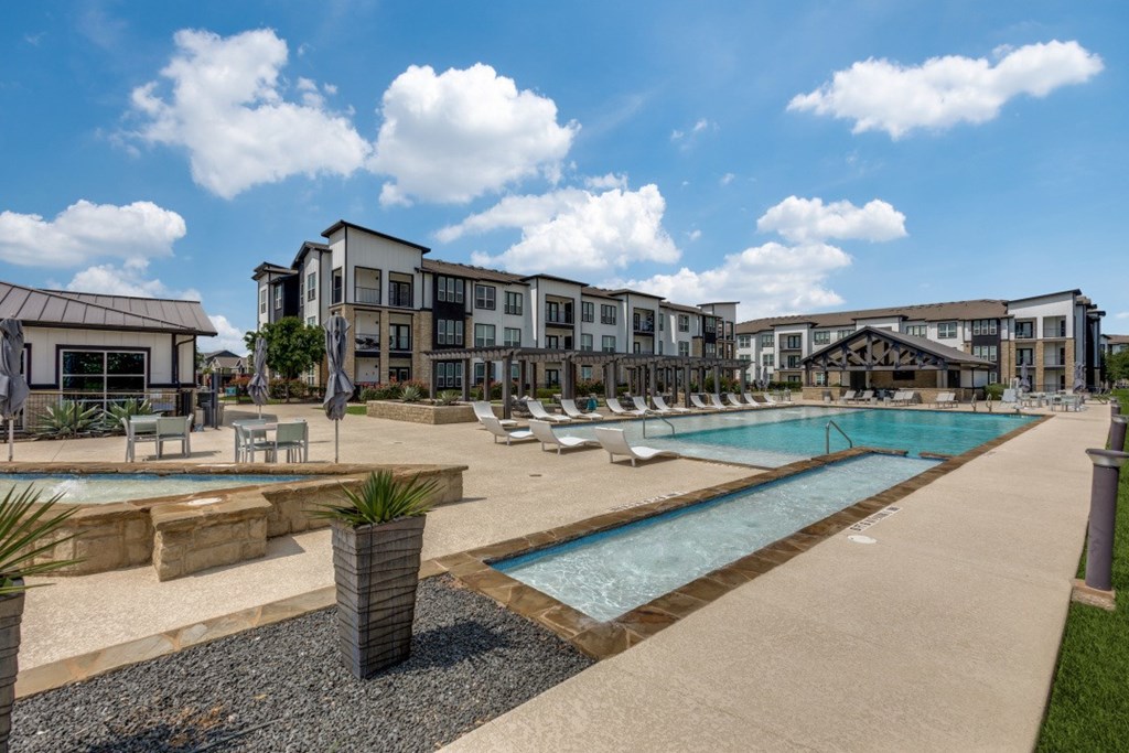 A large outdoor swimming pool surrounded by lounge chairs and umbrellas.