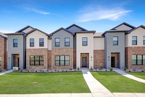 Townhouses in Willow Park for Rent - Willow Crossing - An exterior shot of Willow Crossing's row of brick and white houses with green grass