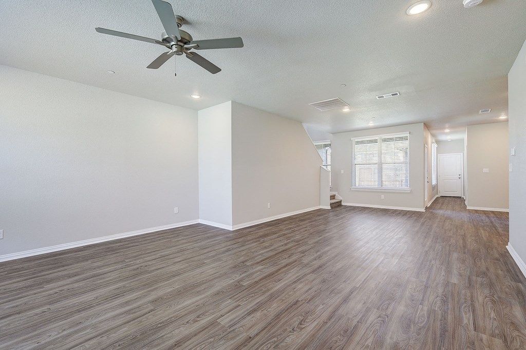 an empty living room with hardwood floors and a ceiling fan