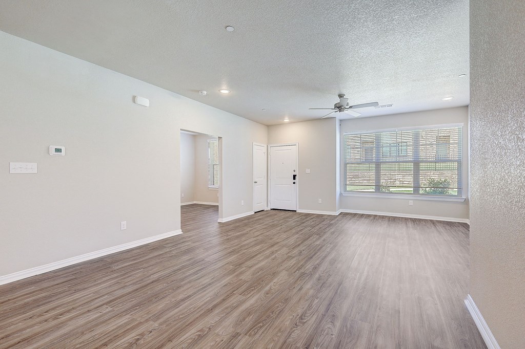 an empty living room with a ceiling fan and a window