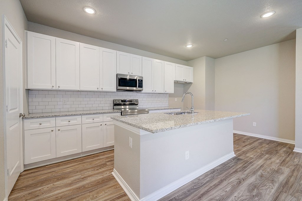 an empty kitchen with white cabinets and a counter top