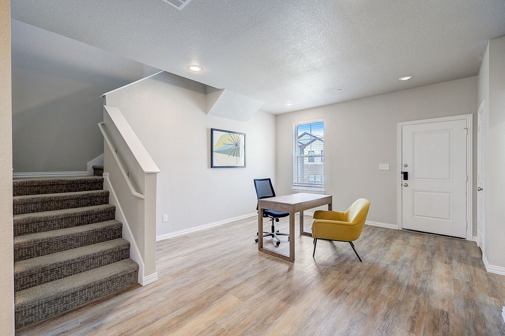 a living room with a staircase and a table and chairs