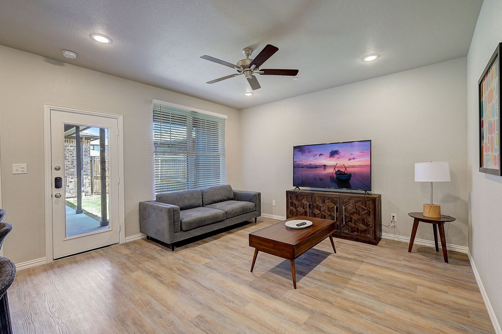 Three BR Townhomes in Willow Park TX - Willow Crossing - An interior shot of the living room featuring wood-style flooring, ceiling fans, and LED lighting