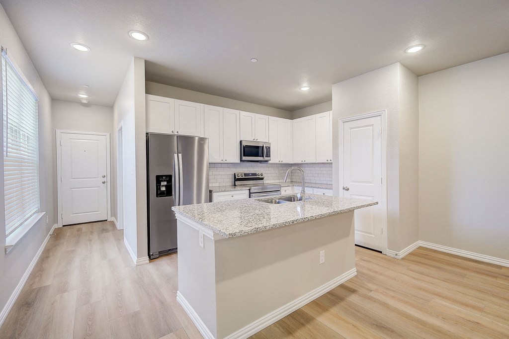 a kitchen with a large island and a stainless steel refrigerator
