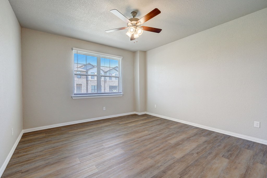 an empty living room with a ceiling fan and a window