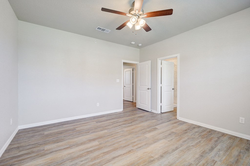 a spacious living room with white walls and a ceiling fan