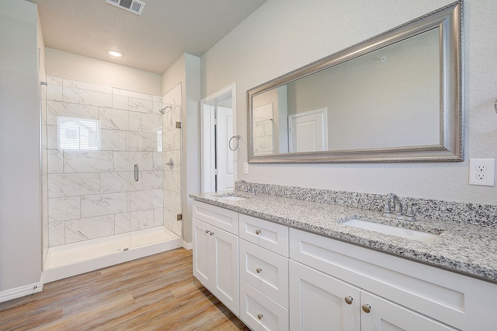 a bathroom with white cabinets and a sink and a shower