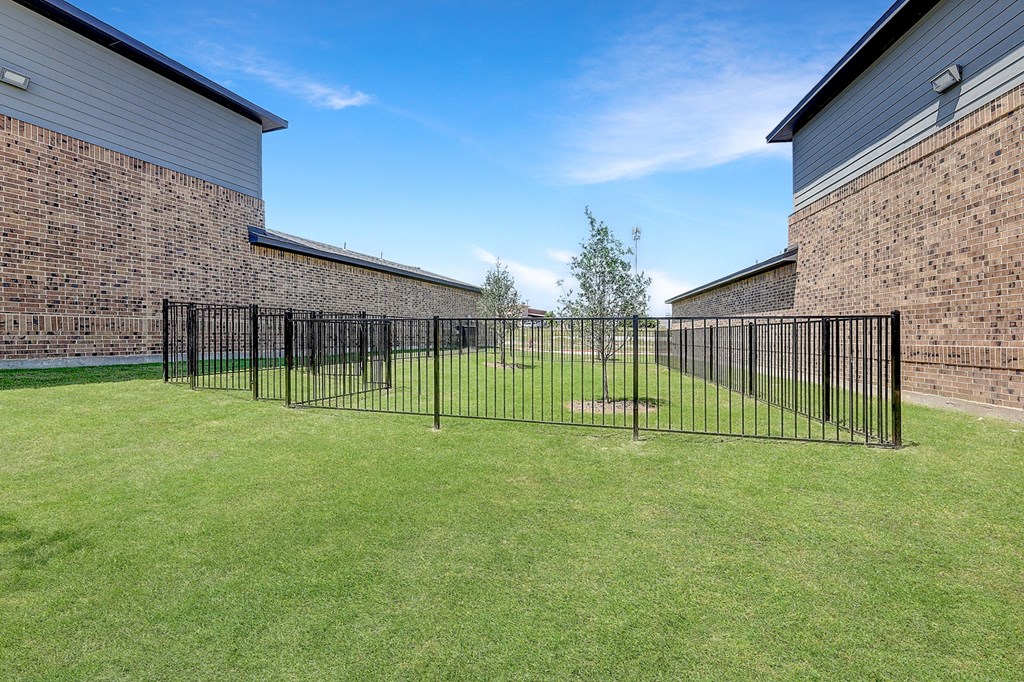 a yard with a fence and a brick building
