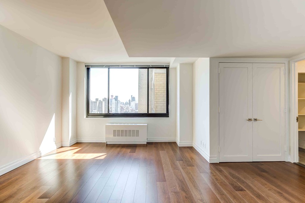 an empty living room with wood floors and a large window