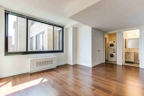 an empty living room with wood floors and a large window