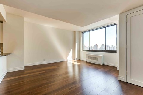 an empty living room with hard wood floors and a large window