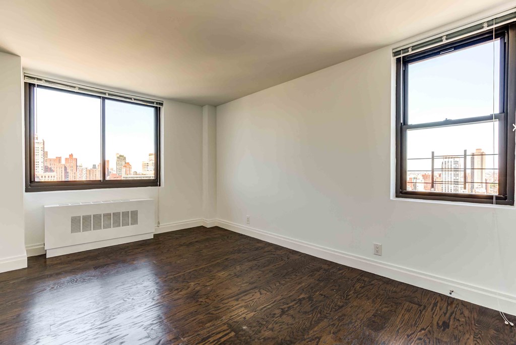 an empty living room with wood floors and two windows
