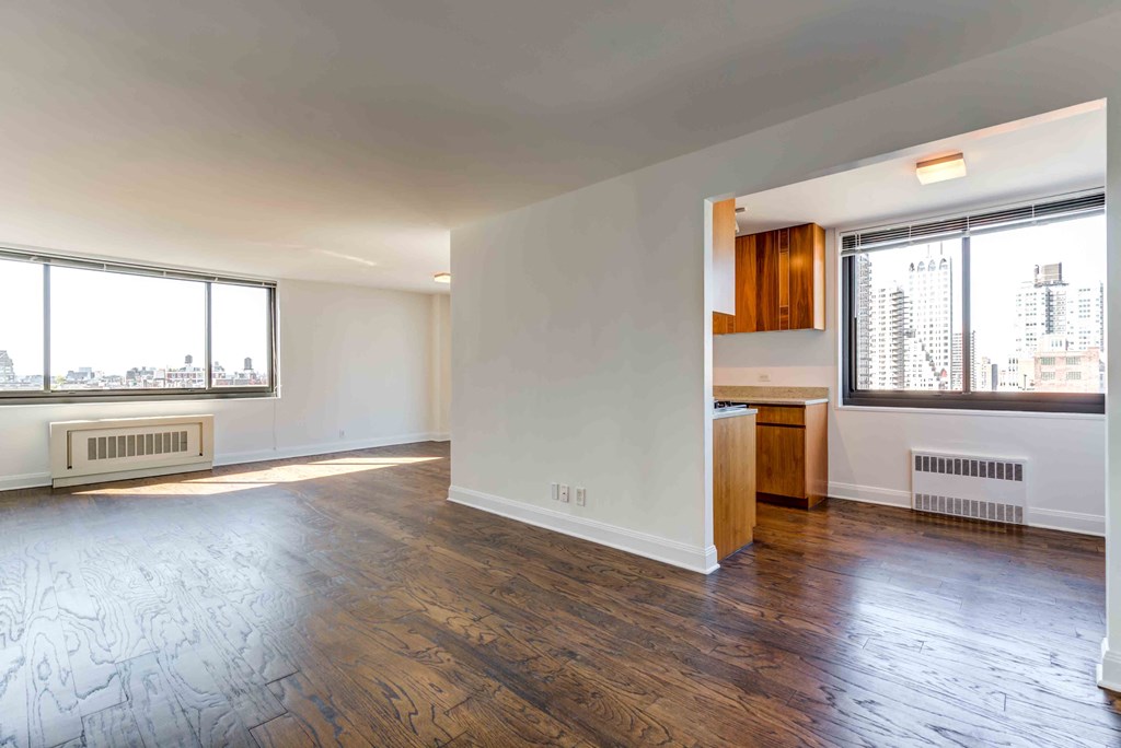 an empty living room with wood flooring and a window