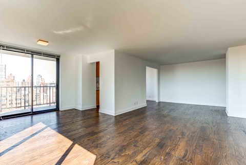 an empty living room with wood floors and a balcony