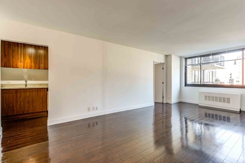 an empty living room with wood floors and a window
