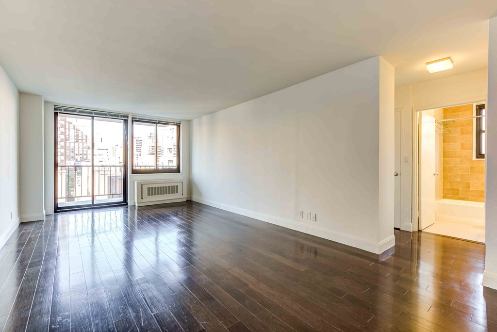 an empty living room with hard wood floors and a window