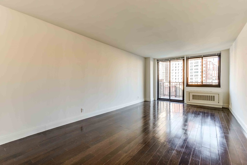 an empty living room with hard wood floors and a window