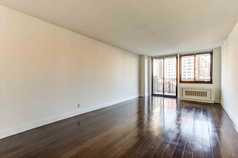 an empty living room with hard wood floors and a window
