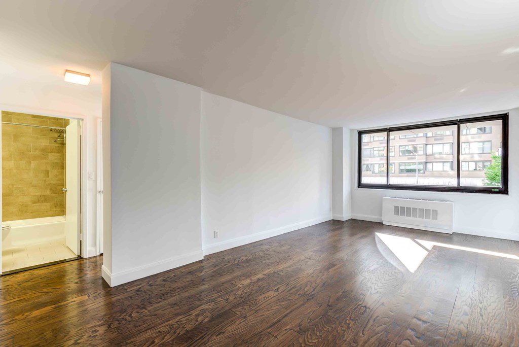 an empty living room with white walls and a large window
