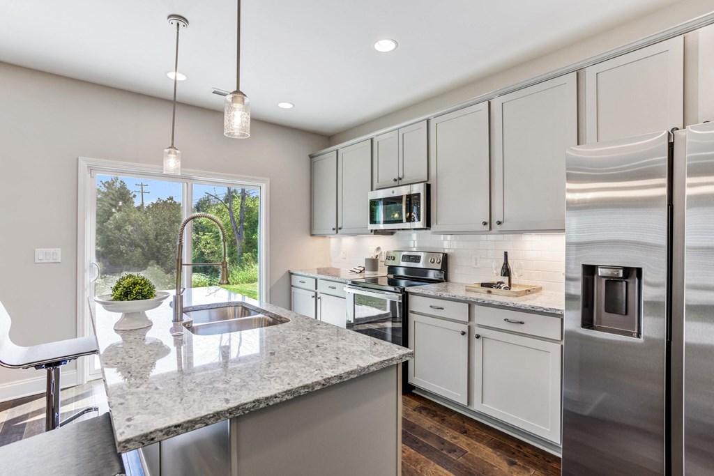 a kitchen with white cabinets and a marble counter top