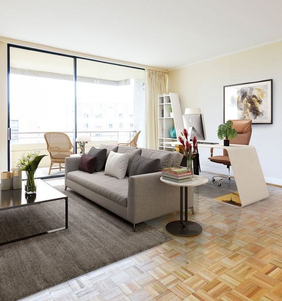 A living room with a grey couch, a coffee table, a chair, a potted plant, a bookshelf, and a painting on the wall.