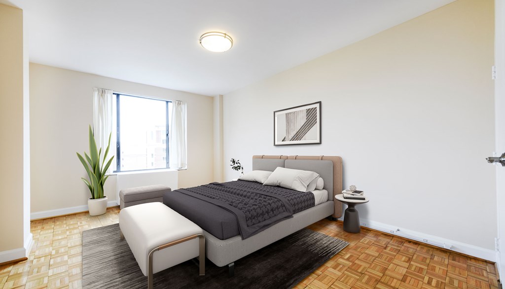 A bedroom with a bed, chair, and potted plant.