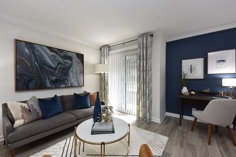 A living room with a grey couch, a coffee table, and a painting on the wall.