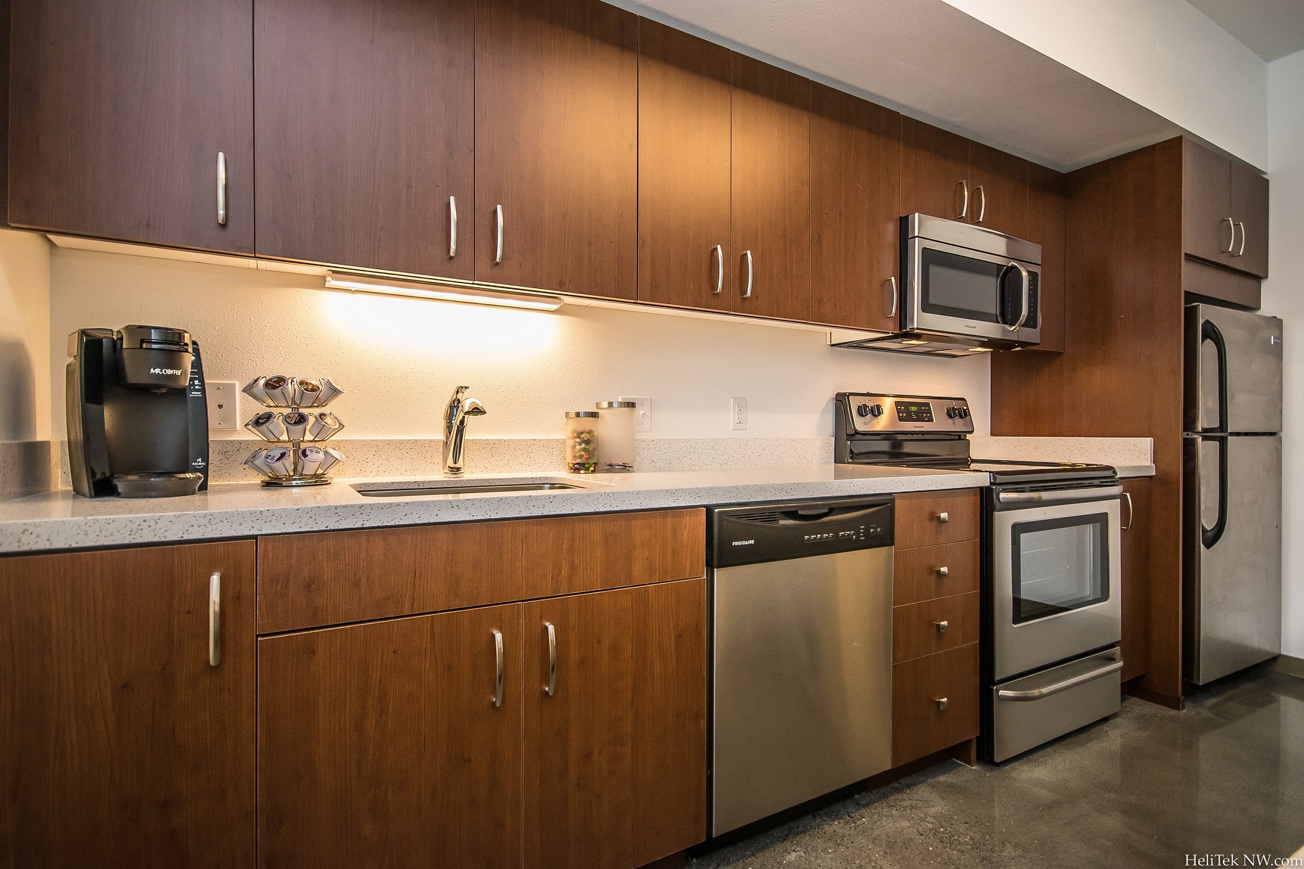 Portland Apartments - Corbett Heights - Chef-Inspired Kitchen with Wood-Style Cabinetry, Polished Concrete Flooring, Quartz Countertops, and Stainless Steel Appliances
