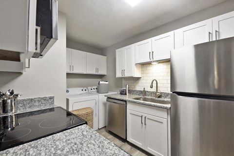 A modern kitchen with white cabinets and stainless steel appliances.