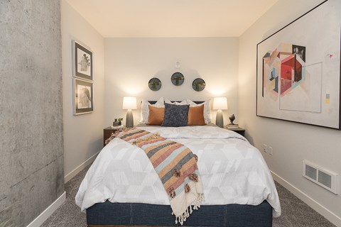 A bedroom with a bed covered in a white comforter and a striped blanket.