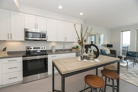 A modern kitchen with a wooden table and bar stools.